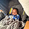 baby, infant, car_seat, blanket, smiling, clothing, indoor, person, child, cute, happy, seat, warm, cozy, fabric, transportation, car, sitting, mittens, portrait