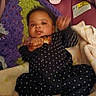 baby, infant, child, portrait, lying_down, snack, food, blanket, polka_dot, clothing, face, eyes, hair, hand, smiling, indoor, cozy, bedding, warning_label, photography