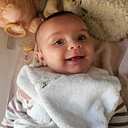 Adèle participe au concours pour gagner de l'argent avec cette photo : baby, smiling, blanket, striped_clothing, plush_toy, soft_texture, infant, face, happy, lying_down, cute, child, indoors, cozy, warm, comfort, portrait, head, eyes, mouth