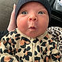 baby, infant, face, beanie, hat, leopard_print, clothing, cute, expression, surprised, person, child, newborn, hand, holding, pattern, zipper, warm, indoor, closeup