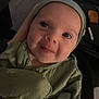 Olivia joined the competition — help win amazing prizes! baby, infant, face, green_clothing, hat, portrait, cute, child, person, indoors, human, smile, wide_eyes, apparel, headwear, young_child, looking_at_camera, sitting, hand, warm_lighting