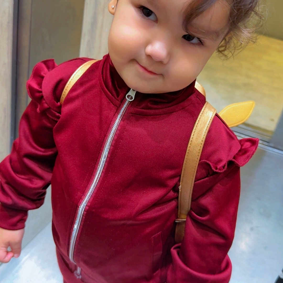 Daowen a rejoint le concours — aidez-le/la à gagner de superbes lots ! backpack, burgundy_outfit, child, curly_hair, cute, fashion, floor, girl, indoor, person, pigtails, playful, portrait, purple_shoes, ruffles, smile, standing, toddler, young_child, zipper