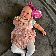 Lexi joined the competition — help win amazing prizes! baby, infant, pink_headband, pink_romper, white_tights, blanket, soft_texture, milestone_sign, lying_down, cute, smiling, child, person, indoors, portrait, headwear, fabric, skin, cheeks, small