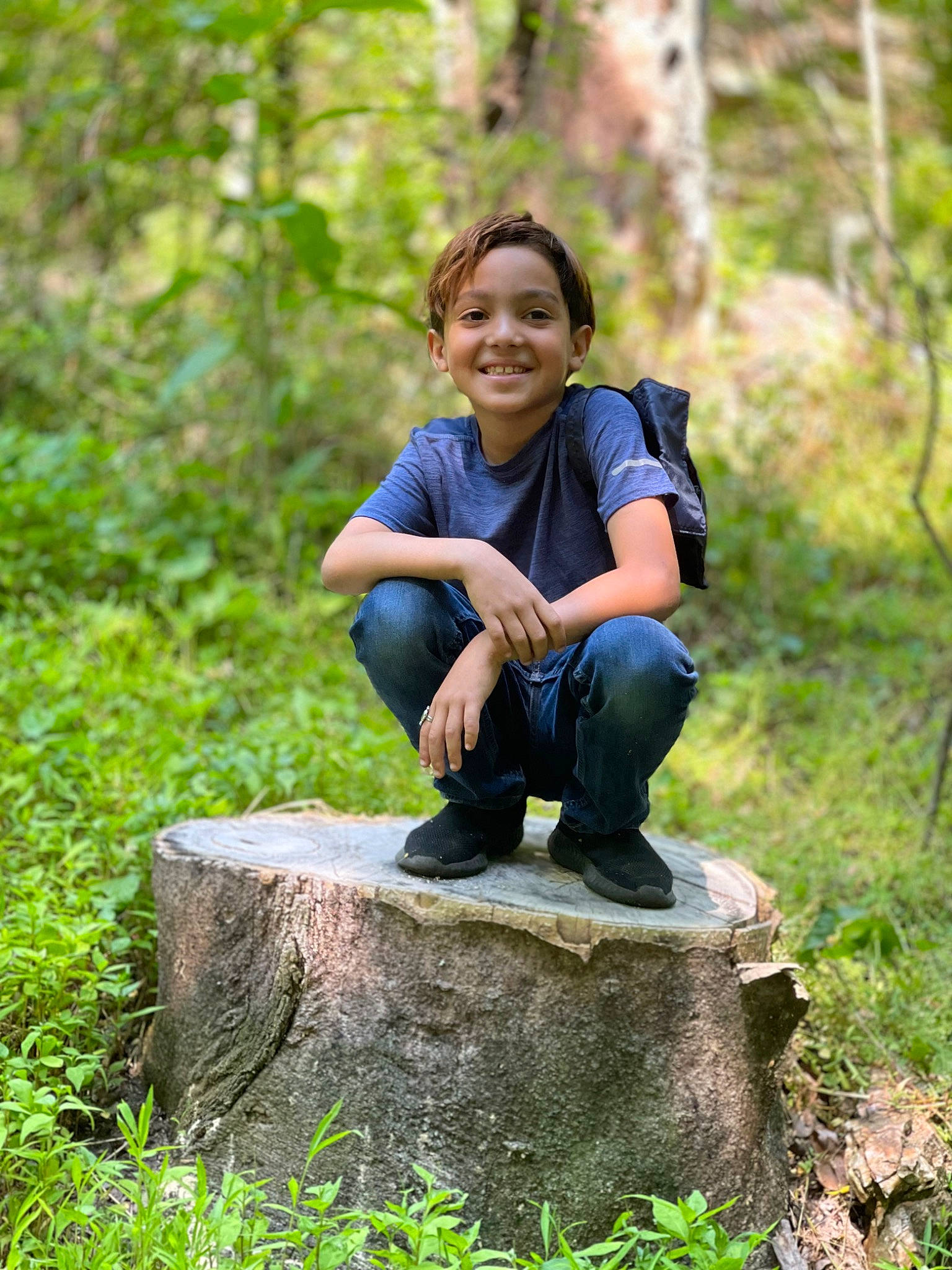 Destin is registered to the contest to win money with this photo: boot, branch, forest, grass, happy, joy, jungle, landscape, leisure, natural_landscape, people_in_nature, person, plant, sitting, smile, soil, terrestrial_plant, tree, trunk, wood