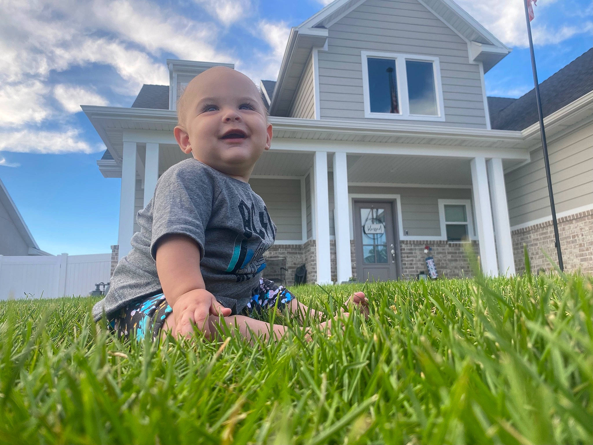Baynx is registered to the contest to win money with this photo: baby, blue, cloud, flooring, fun, grass, grassland, happy, house, joy, landscape, lawn, leisure, meadow, people_in_nature, person, plant, sky, smile, t_shirt