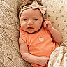 baby, infant, headband, onesie, knitted_pillow, blanket, couch, soft_lighting, portrait, child, cute, indoors, smile, relaxed, person, cozy, fabric, pattern, skin, young