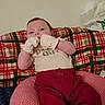 Lagertha joined the competition — help win amazing prizes! baby, infant, child, portrait, face, eyes_open, smiling, sitting, lying_down, mittens, clothing, red_pants, plaid_blanket, cushion, bed, indoors, home, wall, baby_clothes, cozy