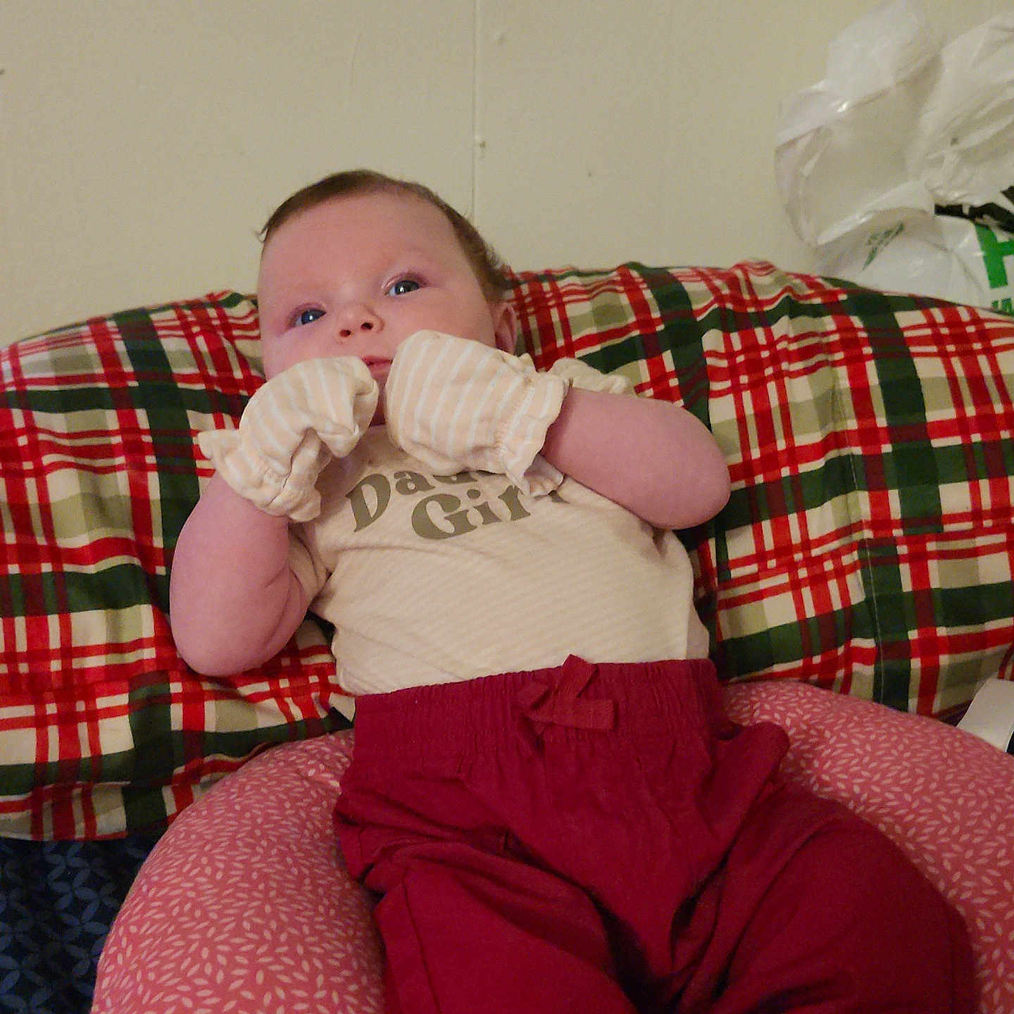 Lagertha joined the competition — help win amazing prizes! baby, infant, child, portrait, face, eyes_open, smiling, sitting, lying_down, mittens, clothing, red_pants, plaid_blanket, cushion, bed, indoors, home, wall, baby_clothes, cozy