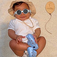 Sajed a rejoint le concours — aidez-le/la à gagner de superbes lots ! 6_months, baby, beige, blue_crocs, child, cool, cute, diaper, fashion, footwear, hands, hat, indoor, legs, milestone, portrait, relaxed, smile, sunglasses, wooden_balloon