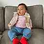 toddler, child, couch, indoor, clothing, vest, striped_shirt, jeans, red_socks, sitting, curious, face, person, furniture, home, casual, cozy, portrait, young_child, comfortable
