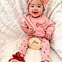baby, infant, child, smiling, headband, bow, pink_clothing, cherry_print, milestone_disc, five_months, red_shoes, bow_shoes, cozy_blanket, sitting, portrait, happy, cute, earrings, small_hands, soft_texture