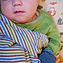 animal_print, baby, blanket, child, cozy, cute, face, green_clothing, indoors, infant, pattern, peaceful, pillow, portrait, resting, sleeping, soft, striped, wrapped, young_child