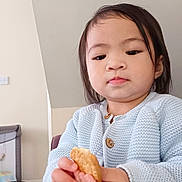 Angela joined the competition — help win amazing prizes! toddler, child, person, indoor, knitwear, sweater, food, biscuit, hand, face, expression, furniture, baby_furniture, wall, button, long_hair, skin, casual, young, focus