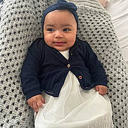 Elyssia a rejoint le concours — aidez-le/la à gagner de superbes lots ! baby, infant, headband_bow, navy_cardigan, white_dress, knitted_blanket, crochet_blanket, bed, smile, face, chubby_cheeks, hands, eyes, portrait, indoors, cozy, cute, lying_down, fabric_texture, soft_light