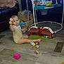 child, toddler, baby, toys, playset, barn_toy, jumper, television, living_room, tile_floor, toy_block, basket, blanket, couch, plastic_toy, sitting, foot, play_time, floor_vent, cute