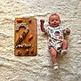 baby, clothing, face, food, hardwood, head, hosiery, newborn, number, person, photography, portrait, sitting, sleeve, sock, stainedwood, symbol, text, toy, wood