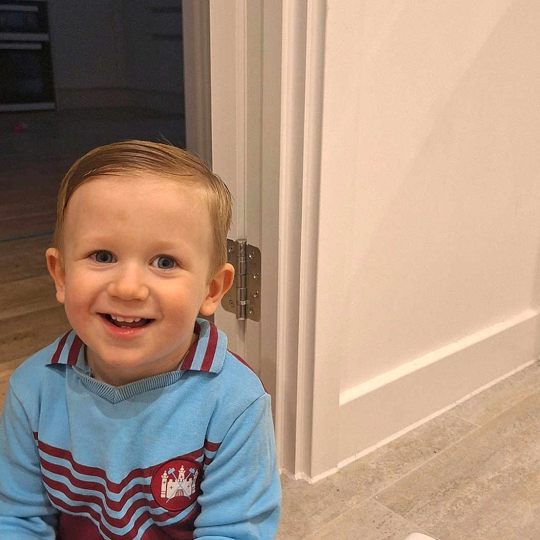 Levi joined the competition — help win amazing prizes! boy, child, clothing, door, electronics, face, happy, head, male, mobilephone, pants, person, phone, photography, plant, portrait, pottedplant, sitting, smile, wood