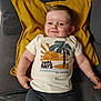 baby, child, smiling, tshirt, couch, pillow, indoor, cute, portrait, happy, infant, person, clothing, sitting, relaxed, home, face, young_child, casual, cozy