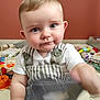 baby, child, blue_eyes, curious, overalls, white_shirt, toys, play_mat, indoor, person, chubby_cheeks, short_hair, button_straps, colorful, blurred_object, floor, candid, portrait, cute, young_child