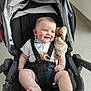 baby, smiling, stroller, blanket, blue_eyes, shorts, white_shirt, pacifier, indoor, child, happy, seat_belt, barefoot, infant, cute, person, toddler, furniture, portrait, comfort