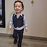 child, toddler, boy, smiling, happy, portrait, standing, walking, formalwear, vest, dress_shirt, bow_tie, trousers, dress_shoes, curly_hair, indoors, hallway, carpet, wall, mirror