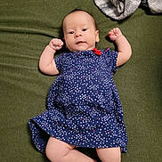 Amara is registered to the contest to win money with this photo: baby, infant, child, dress, blue_dress, stars_pattern, blanket, green_blanket, gray_blanket, lying_down, raised_arms, curious_expression, indoor, soft_texture, cute, small_fists, person, infant_clothing, portrait, newborn