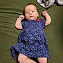 baby, infant, child, dress, blue_dress, stars_pattern, blanket, green_blanket, gray_blanket, lying_down, raised_arms, curious_expression, indoor, soft_texture, cute, small_fists, person, infant_clothing, portrait, newborn
