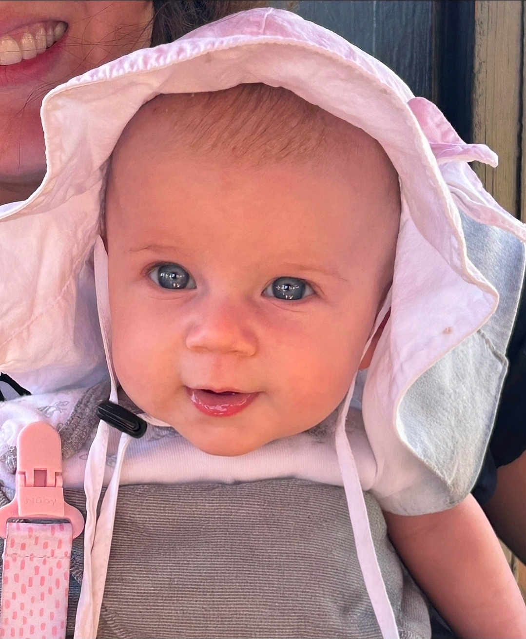 Quinn joined the competition — help win amazing prizes! baby, child, face, hat, sun_hat, blue_eyes, close_up, smile, outdoor, daylight, person, cute, infant, clothing, straps, pink_clip, happy, skin, headwear, portrait