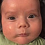 baby, close_up, face, chubby_cheeks, green_clothing, button, infant, skin, eyes, expression, head, portrait, child, young, cute, indoors, person, human, small, adorable