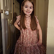 Addy joined the competition — help win amazing prizes! child, girl, smiling, dress, floral_pattern, long_hair, indoor, door, baby_gate, hand_on_hip, happy, person, portrait, standing, room, wall, floor, light, young, casual