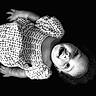 baby, child, portrait, black_and_white, lying_down, wide_eyes, curly_hair, patterned_clothing, gingham, floral, dress, infant, face, eyes, indoor, studio, photography, monochrome, adorable, close_up