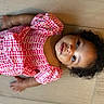 child, girl, toddler, portrait, curly_hair, smiling, pink_dress, gingham, dress, sitting, floor, tile, indoor, overhead_view, face, eyes, barefoot, happy, fashion, photography
