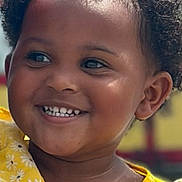 Londynn is registered to the contest to win money with this photo: child, toddler, smiling, curly_hair, yellow_dress, flower_pattern, portrait, happy, face, skin, eyes, person, cute, outdoor, sunlight, clothing, baby, young_child, expression, closeup