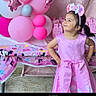 child, girl, birthday, party, pink, dress, bow, headband, balloons, gifts, table, decorations, smiling, portrait, indoors, celebration, playful, standing, hands_on_hips, colorful
