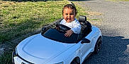 Isodaurío participe au concours pour gagner de l'argent avec cette photo : toddler, toy_car, audi, white_car, smiling_child, outdoor, driveway, sunny, greenery, grass, trees, small_vehicle, child, happy, playing, daytime, road, miniature, automobile, person