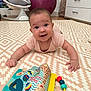 baby, infant, smiling, play_mat, toy, soft_toy, indoor, child, happy, crawling, patterned_rug, colorful, cute, person, floor, young_child, cheerful, clothing, bright, home