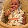 baby, high_chair, infant, smiling, face, hand, blanket, plush_toy, kitchen, seat, child, cute, happy, fingers, clothing, indoor, person, safety_strap, toy, expression