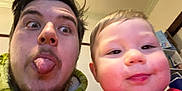 Brenn-Arthur joined the competition — help win amazing prizes! adult, baby, background, casual, child, closeup, face, fun, hair, hoodie, indoor, person, playful, portrait, red_clothing, shelf, silly_face, smile, tongue, young_child