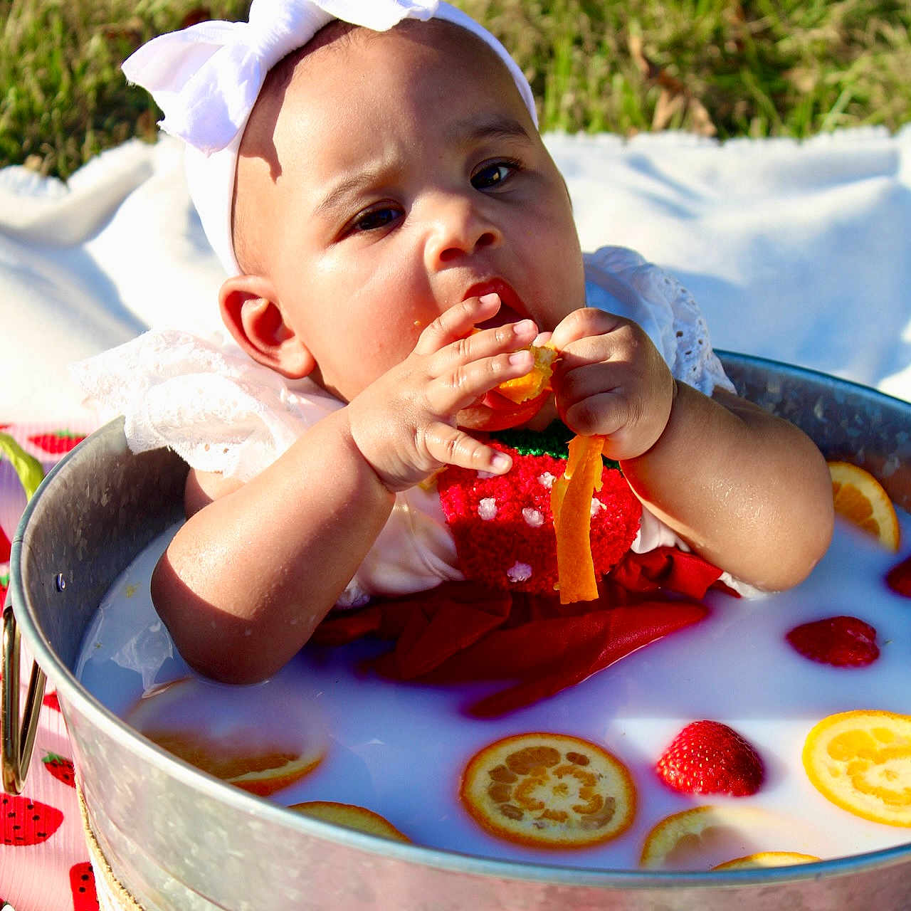 Auvree joined the competition — help win amazing prizes! baby, curious_expression, cute, decorative_bow, face, fruit, grass, hand, headband, infant, metal_tub, milk_bath, orange_slices, outdoor, picnic_blanket, red_clothing, skin, strawberries, summer, sunlight