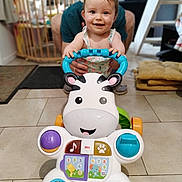 Zoey participe au concours pour gagner de l'argent avec cette photo : baby, baby_gate, child, colorful, cushion, cute, early_steps, floor, hands, happy, home, indoor, person, play, smiling, support, tiles, toy, walker, zebra