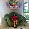 Ashley joined the competition — help win amazing prizes! child, smile, red_shirt, nike, leaf_chair, cabbage_patch_kids, babyland_sign, indoor, window, greenery, tile_floor, person, seated, casual_clothing, plush_chair, happy, young, home_decor, natural_light, portrait