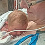 Conan is registered to the contest to win money with this photo: baby, newborn, mother, hospital, medical_equipment, glasses, skin, face, love, care, affection, closeup, patient_gown, tube, healthcare, parent, infant, hospital_room, comfort, tenderness