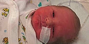 Conan is registered to the contest to win money with this photo: newborn, baby, infant, pacifier, mittens, hospital, medical_tape, face, lying_down, clothing, cute, sleepy, bed, blanket, healthcare, person, child, hospital_bed, wrapped, soft