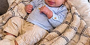 Noham participe au concours pour gagner de l'argent avec cette photo : baby, infant, blanket, plaid, couch, pillow, smile, face, clothing, socks, comfortable, cozy, indoors, portrait, young_child, light_blue, beige, soft_texture, relaxed, cute