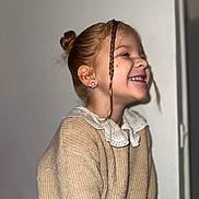 Shellya participe au concours pour gagner de l'argent avec cette photo : braided_strand, braids, candid, child, cozy, ear, earring, girl, hair_bun, hairstyle, indoor, knitwear, lace_collar, laughing, portrait, profile_view, smiling, sweater, teeth, wall_background