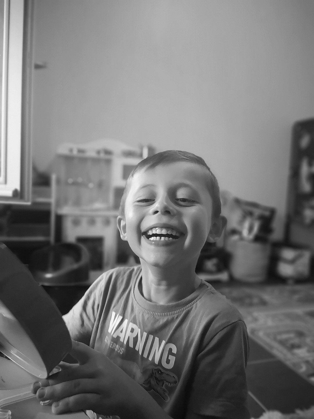 Erwan participe au concours pour gagner de l'argent avec cette photo : black_and_white, child, fun, happy, joy, laugh, monochrome, monochrome_photography, person, portrait_photography, room, sitting, smile, standing, style, t_shirt, toddler