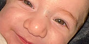 Noah is registered to the contest to win money with this photo: baby, close_up, face, smile, white_shirt, child, infant, happy, cute, skin, portrait, eyes, cheeks, expression, young, person, head, indoors, cozy, soft_background
