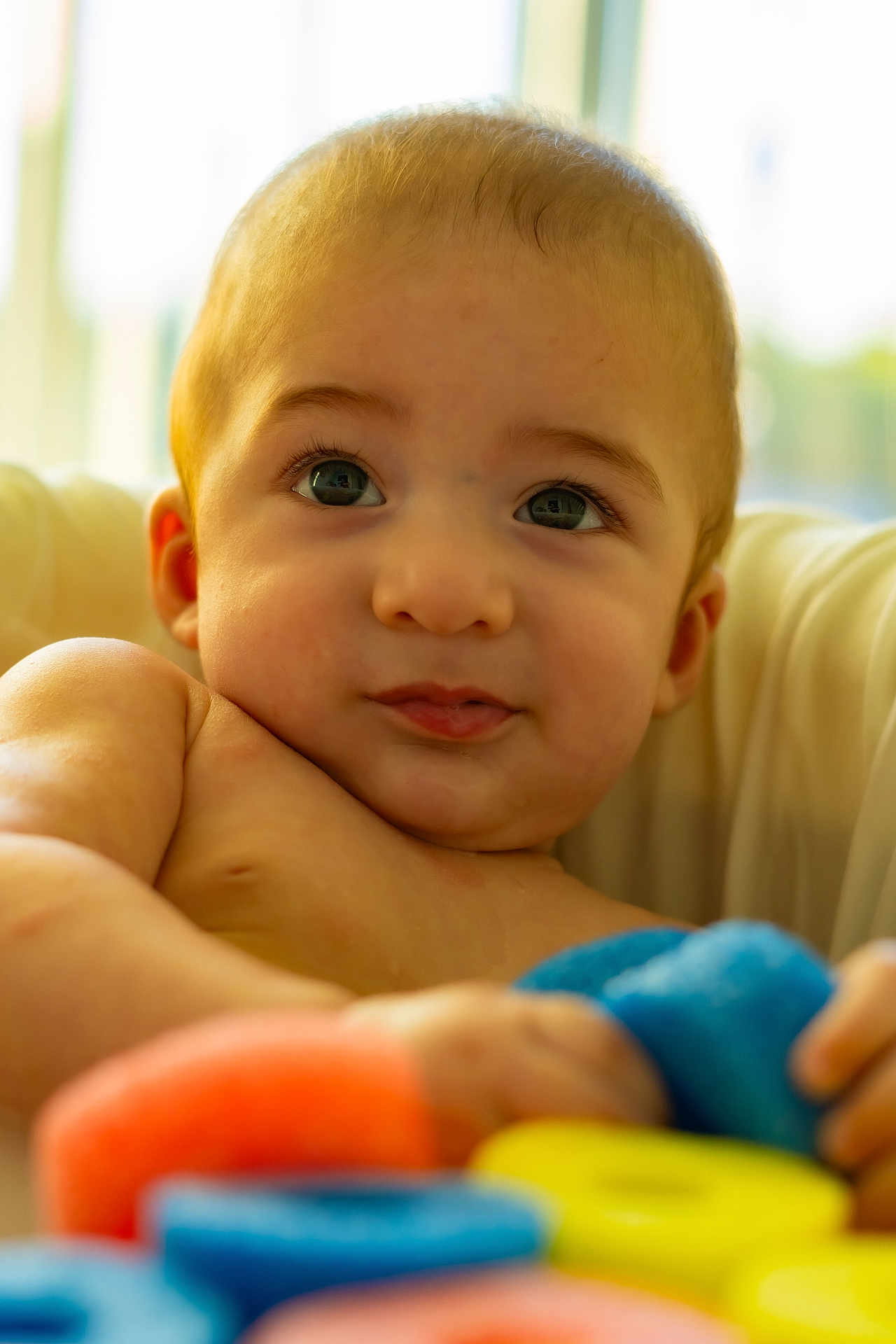 Noah is registered to the contest to win money with this photo: baby, child, infant, face, eyes, skin, soft, colorful, foam_rings, toy, hand, indoors, close_up, portrait, cute, expression, young, warm_light, cozy, background_blur