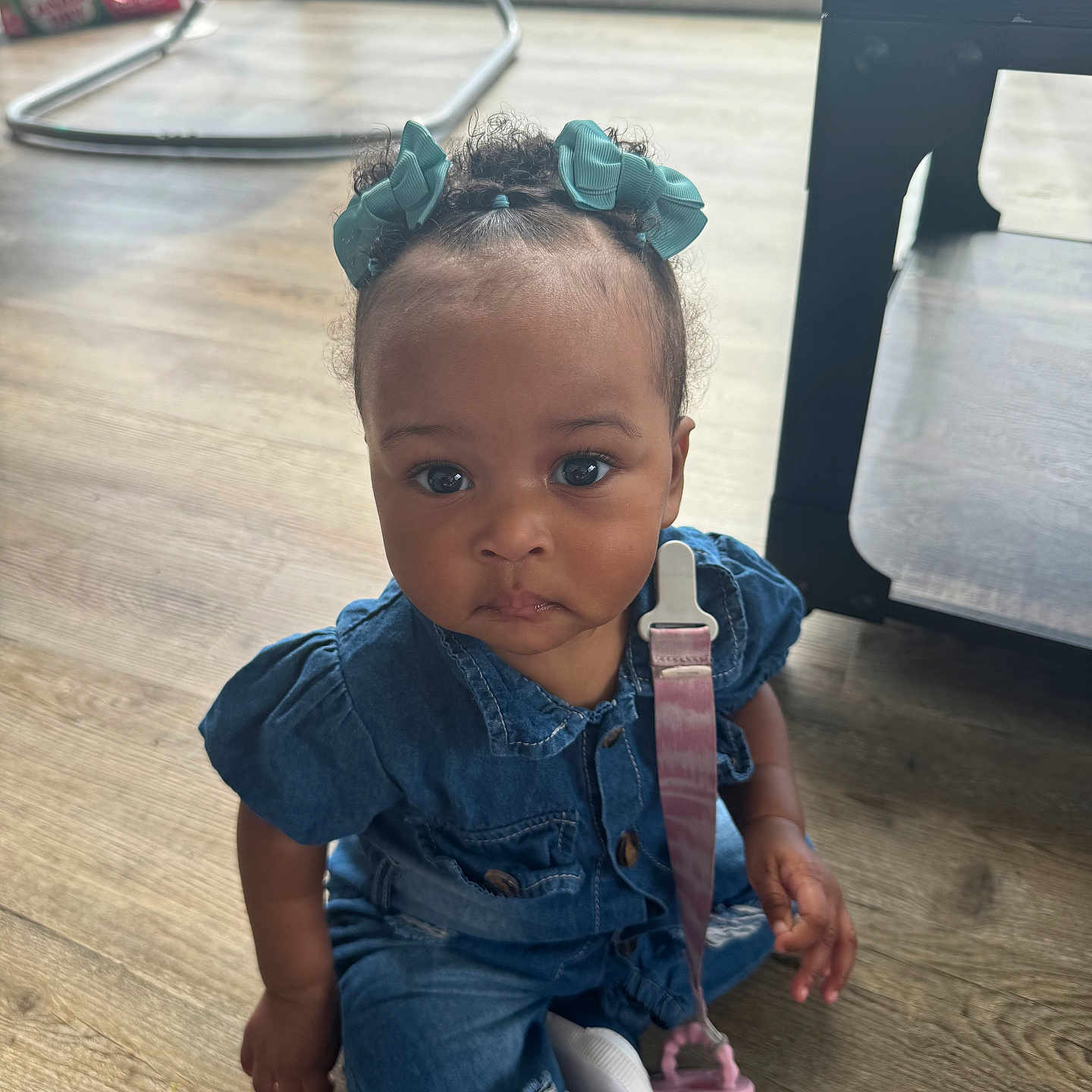 Keyoni is registered to the contest to win money with this photo: baby, baby_rocker, blue_bows, child, clothing, curly_hair, cute, denim, expression, face, flooring, footwear, hands, indoor, infant, pacifier, sitting, table, toddler, wooden_floor