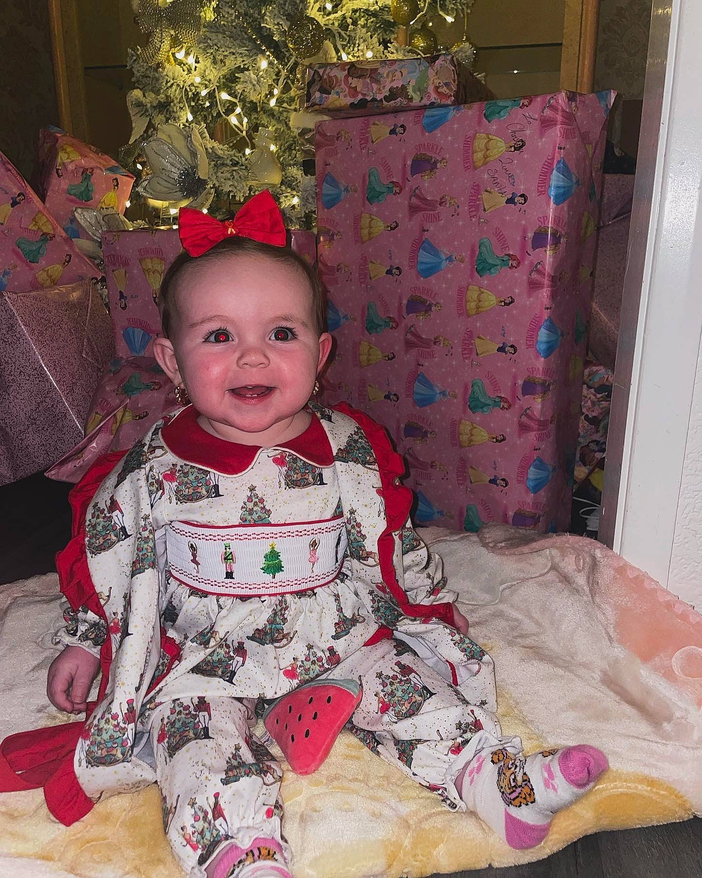 Christina is registered to the contest to win money with this photo: baby, baby_toddler_clothing, child, christmas, event, face, fun, happy, head, holiday, human_body, joy, lap, pajamas, person, pink, sitting, sleeve, smile, standing